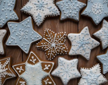 Ahşap arka planda kremayla kaplı ev yapımı zencefilli kurabiyeler, Noel şekilli lezzetli kurabiyeler.