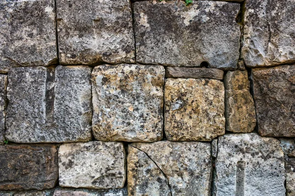 A masonry wall of multicolored stones or blocks.