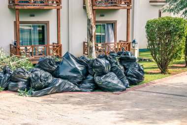 Şehirdeki yol kenarındaki çöp yığınları, kirlilik çöpleri. Siyah çöp torbası, evin önündeki plastik çöp torbaları..