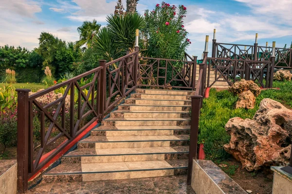 Outdoors. An old wooden staircase with railings, leading upwards. Blue sky above.