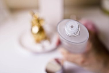 Kadın elinde bir kavanoz sıvı nemlendirici yüz toniği. Beyaz bulanık arkaplan.