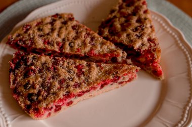 Tatlı böğürtlenli fırınlanmış lezzetli turtanın yakından görüntüsü beyaz bir tabakta. Turta üç dilime bölündü..