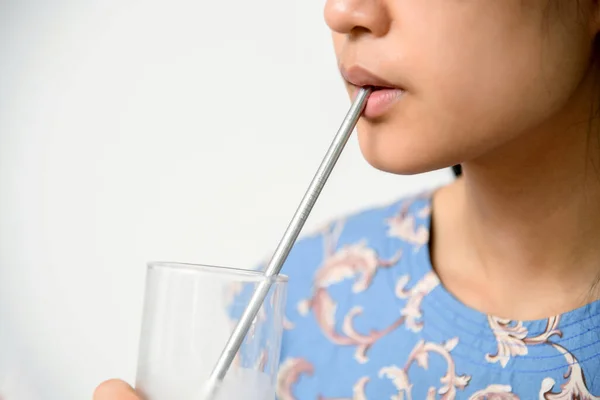 Bir kadın beyaz arka planda plastik samanı azaltmak için paslanmaz saman kullanır