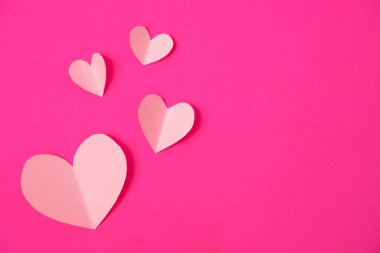 Pembe kağıt üzerinde uçan kalp şeklinde kağıt elementler. Aşk ve Sevgililer Günü konsepti. Doğum günü tebrik kartı tasarımı.