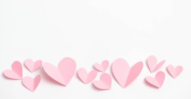 Beyaz kağıt üzerinde uçan kalp şeklinde kağıt elementler. Aşk ve Sevgililer Günü konsepti. Doğum günü tebrik kartı tasarımı.