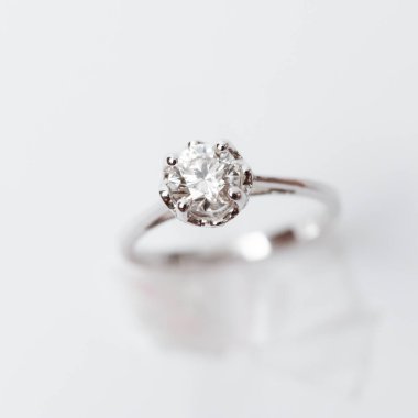 Beyaz arka planda zarif bir nişan yüzüğü yakın plan. Aşk, düğün ve Sevgililer Günü konsepti. Sığ alan derinliğine sahip seçici odak.