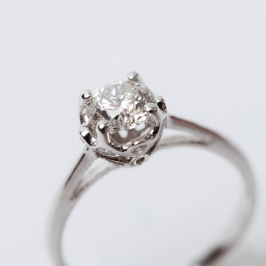 Beyaz arka planda zarif bir nişan yüzüğü yakın plan. Aşk, düğün ve Sevgililer Günü konsepti. Sığ alan derinliğine sahip seçici odak.