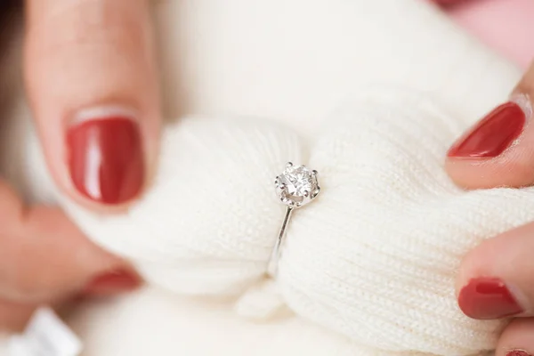 Close up of an elegant engagement diamond ring on woman finger with pink sweater winter clothe. love, wedding and Valentine\'s day concept.