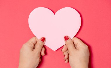 Beyaz arka planda kalp şeklinde pembe boş kağıtlar tutan kadınları kapatın. Boş alan, metin pankartlı yazı için hazır. Sevgililer Günü konsepti