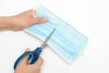 Kızın elleri, çöpleri atmadan önce kullanılan tıbbi koruyucu maskeyi kesmek ya da yok etmek için makas kullanıyor. Coronavirus ya da Covid-19 salgını sırasında maskenin tekrar satılmasını engelliyor.