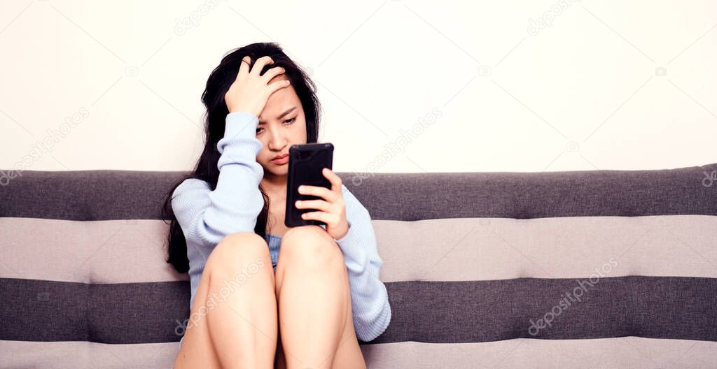 An asian woman getting anxiety and depression after checking news in mobile phone about global pandemic. Lockdown mental health. Coronavirus outbreak
