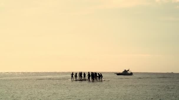 Um grupo de pessoas está praticando ioga nas pranchas de jantar. Ioga de remo. Belo mar calmo e céu limpo. Calma e equilíbrio. Yoga no mar. Asanas e equilíbrio . — Vídeo de Stock