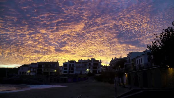Silhouette of trees and houses on a background of beautiful sunset clouds. The setting sun colors the clouds in fiery colors. Yellow and orange glowing clouds. Breathtaking view. Endless sky. — Stockvideo