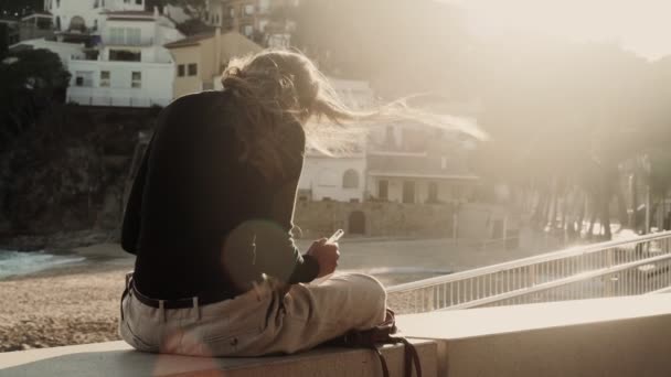 The artist makes sketches on the sunny promenade. Girl draws a coastal landscape with white mediterranean houses. Black and white drawing by liner on white paper. Golden sunlight. Drawing outdoors. — 비디오