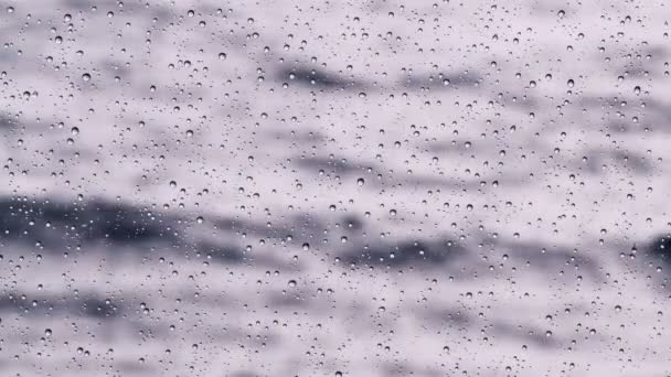 Gotas de chuva em um painel de janela. Mar severo fora da janela. Onda de luz na superfície do mar. O mar dramático. Tempo nublado e chuva. Tranquilidade e pacificação . — Vídeo de Stock