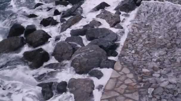 Viharhullámok csapódtak a sziklák közé a töltésnél. Drámai tenger. Vihar. Fehér tengeri hab a köveken. — Stock videók