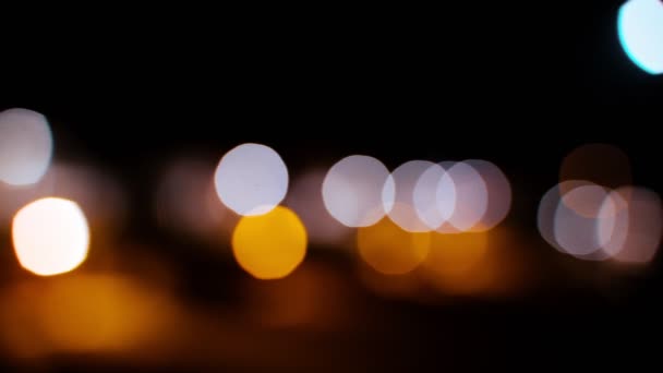 Miasto rozpuszcza się w wieczornych światłach. Nokturnowa perspektywa miejskich świateł. Piękne żółte, białe, pomarańczowe i różowe odbicia światła nocnego miasta. Zamazany blask miasta — Wideo stockowe