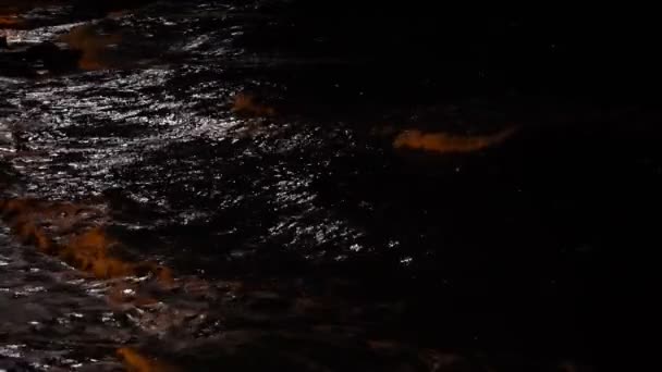 Las olas de tormenta salpican en la noche. Vista nocturna sobre el mar. La luz de la luna reflejándose en las olas. Brillante resplandor en la superficie del agua. Mar dramático. Tormenta . — Vídeo de stock