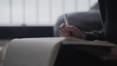 Sanatçı çizimler yapar. Kız çizim defterine bir şeyler çiziyor. Beyaz kağıda siyah beyaz çizim. Robot resme yakın çekim. El çizimi. Çizim ve çizim.