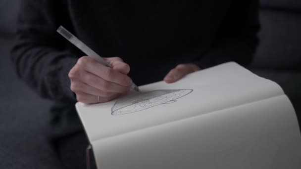 Der Künstler skizziert. Mädchen zeichnet einen Korb in ein Skizzenbuch. Schwarz-weiße Zeichnung von Liner auf weißem Papier. Nahaufnahme zum Skizzieren. Handzeichnung. Skizzieren und Zeichnen. — Stockvideo