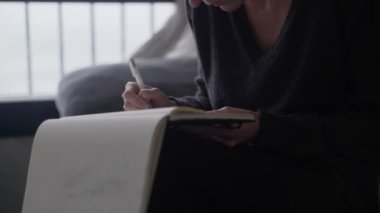 Sanatçı çizimler yapar. Kız çizim defterine bir sepet çiziyor. Beyaz kağıda siyah beyaz çizim. Robot resme yakın çekim. El çizimi. Çizim ve çizim.