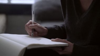 Sanatçı çizimler yapar. Kız çizim defterine bir sepet çiziyor. Beyaz kağıda siyah beyaz çizim. Robot resme yakın çekim. El çizimi. Çizim ve çizim.