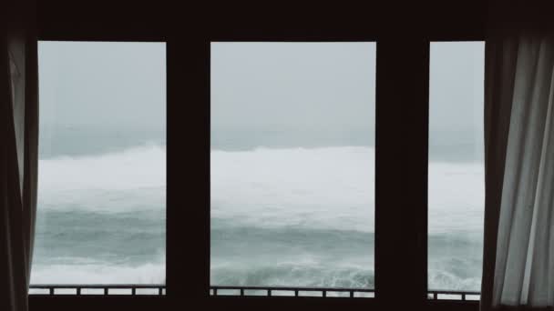 Utsikt över det stormiga havet från fönstret. Tittar på stormen. Svårt rasande hav. Stora vågor. Vindstarkt regnigt väder. Utsikt över det dramatiska havet från fönstret. — Stockvideo
