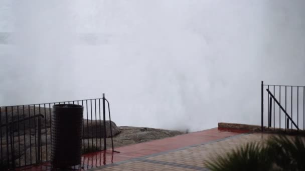 Uitzicht op de stormachtige zee vanaf de promenade. De golven raakten de kust. Naar de storm kijken. Klein dorp tijdens een storm. Ernstige woeste zee. Grote golven. Winderig regenweer. Zicht op de dramatische oceaan. — Stockvideo