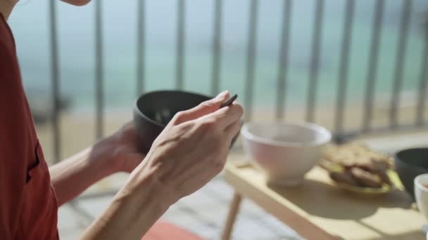 Colazione sulla terrazza. Picnic sulla terrazza soleggiata. Colazione sana. Ragazza mangia palline di mais al cioccolato con latte.. Gustosa colazione sana con fiocchi, latte e biscotti. Tè mattutino. Prodotti ecologici . — Video Stock