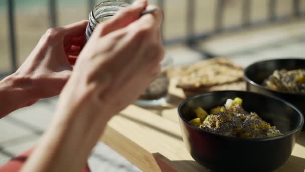 Breakfast on the terrace. Picnic on the sunny terrace. Healthy breakfast. Girl adds honey to oatmeal. Tasty healthy porridge with nuts, fruits and honey. Morning tea. Eco products. Diet breakfast. — Stock Video