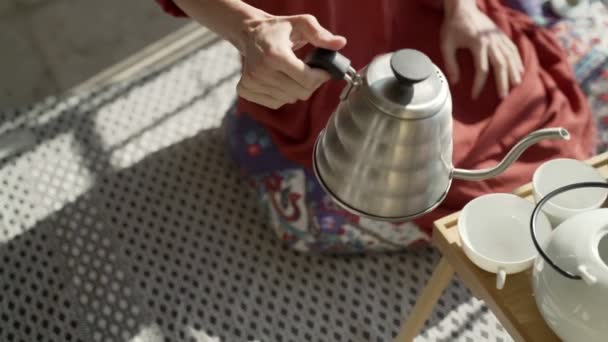 Gezond ontbijt op het terras. Picknick op het zonnige terras. Het meisje maakt thee. Giet kokend water in een ketel. Lekkere gezonde pap met noten, fruit en honing. Goedemorgen thee. Milieuproducten. — Stockvideo