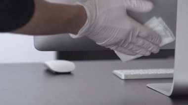 Dezenfekte. Virüs salgını için önlemler. Coronavirus karantinası. Lateks eldivenli eller bilgisayar monitörünü dezenfektanla siler. Alkolle yüzey tedavisi. Evde kal. Salgın