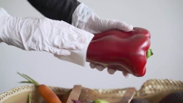 A woman in latex gloves takes a red bell pepper from a grocery basket and wipes it with a disinfector. Disinfection. Precautions for the epidemic of the virus. Coronavirus quarantine. Safe shopping. — Stock Video