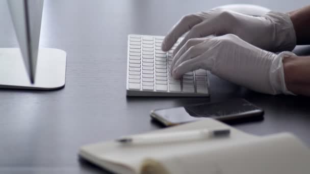 一个男人在家里工作。手拿着乳胶手套在键盘上打字.总部。预防该病毒的流行.Coronavirus检疫呆在家里在家工作。爆发。小心点. — 图库视频影像