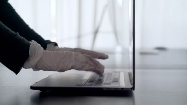 En kvinna arbetar hemifrån. Händerna i latexhandskar skriver på laptopen. Hemmakontoret. Försiktighetsåtgärder mot virusepidemin. Coronavirus-karantän. Stanna hemma. Jobba hemifrån. Utbrott. Skydda dig.. — Stockvideo