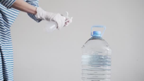 Desinfección. Precauciones para la epidemia del virus. Cuarentena por Coronavirus. Mujer con guantes de látex limpie el mango y la tapa de una botella de agua con un desinfectante. Tratamiento superficial con alcohol . — Vídeos de Stock