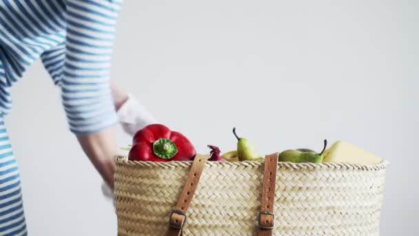 Uma mulher com luvas de látex coloca frutas e vegetais em uma cesta. Compras seguras. Precauções para a epidemia do vírus. Quarentena do Coronavírus. Fica em segurança. Protecção das mãos . — Vídeo de Stock