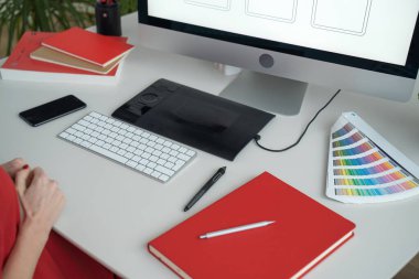 Web tasarımcısı iş başında. Grafik tasarımcısı. Mobil uygulama tasarımı. Tasarımcı masaüstü. UX, UI tasarımı. Bir bilgisayar ekranındaki mobil uygulamanın küçük resimleri. Aletler, çizim defteri ve telefon masada.