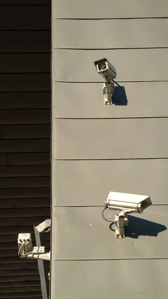 Urbane Szene. Überwachungskameras an einer grauen Wand. Sicherheit. Die helle Sonne fällt auf die Wand. Sicherheitstechnologie. — Stockfoto