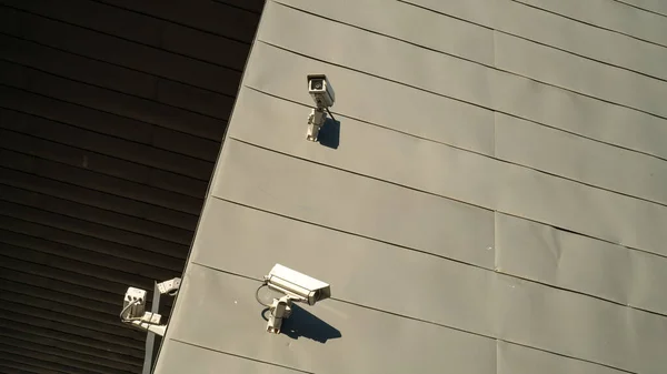 Miejska scowość. Kamery na szarej ścianie. Bezpieczeństwo i ochrona. Jasne słońce pada na ścianę. Technologia bezpieczeństwa. — Zdjęcie stockowe