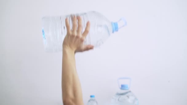 Deporte en casa. Entrenamiento en casa. Hombre haciendo ejercicios usando una botella de agua plástica como una campana de agua. Ejercicios. Deporte con herramientas improvisadas. Quédate en casa. Manténgase en forma durante la cuarentena. Biceps, tríceps — Vídeos de Stock
