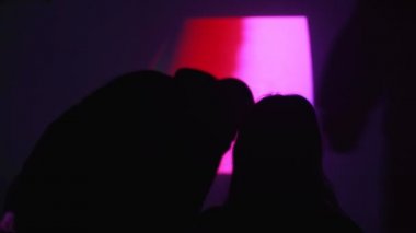 Duvardaki ekranın arkasında birbirine aşık bir çiftin silueti. Bir çift projektörle film izliyor. Evde ne yapacağım? Evde film izliyordum. Evde kal. Evde iyi eğlenceler..