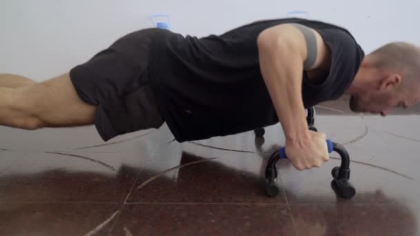 Desporto em casa. Treino em casa. Um homem a fazer exercícios na prancha. Push-ups e exercícios abdominais. Desporto com ferramentas improvisadas. Fica em casa. Mantenha-se em forma durante a quarentena. Exercício de alpinistas . — Vídeo de Stock