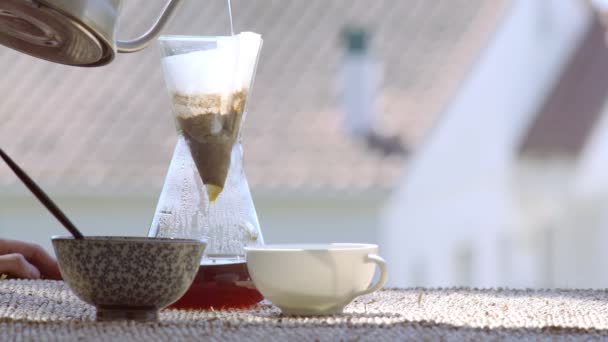 Robię specjalną kawę w domu. Filtrować kawę na tarasie z widokiem. Dziewczyna wlewa ciepłą wodę do dzbanka do kawy. Zostań w domu. Domowy barista. Domowe jedzenie. Specjalne narzędzia do kawy. Uważaj na siebie.. — Wideo stockowe