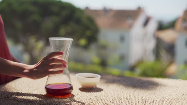 Ik maak thuis speciale koffie. Filter koffie op het terras met uitzicht. Een meisje giet koffie uit een pot in een witte porseleinen beker. Blijf thuis. Thuis barista. Speciaal koffiegereedschap. Blijf veilig.. — Stockvideo