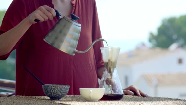 Evde özel kahve yapıyorum. Terasta manzaralı kahve filtresi. Kız kahve makinesine sıcak su döküyor. Evde kal. Ev kahvecisi. Ev yemeği. Özel kahve aletleri. Kendine dikkat et.. — Stok video