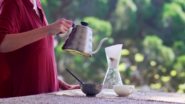 Making speciality coffee at home. Filter coffee on the terrace with a view. Girl pours hot water into a coffee pot. Stay home. Home barista. Home cooking. Speciality coffee tools. Stay safe. — Stock Video