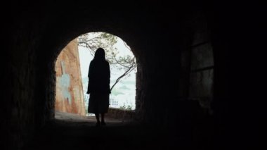 Beyaz çizgili elbiseli ve gri ceketli bir kız sahil yolunda yürüyor ve taş tünelden geçiyor. Uzun saçlı kadın güzel kırsalda yürüyor. Cennet manzarasında altın bir ışık.