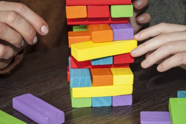 Mom and daughter play a board game. Build a tower of wooden kerpich. 