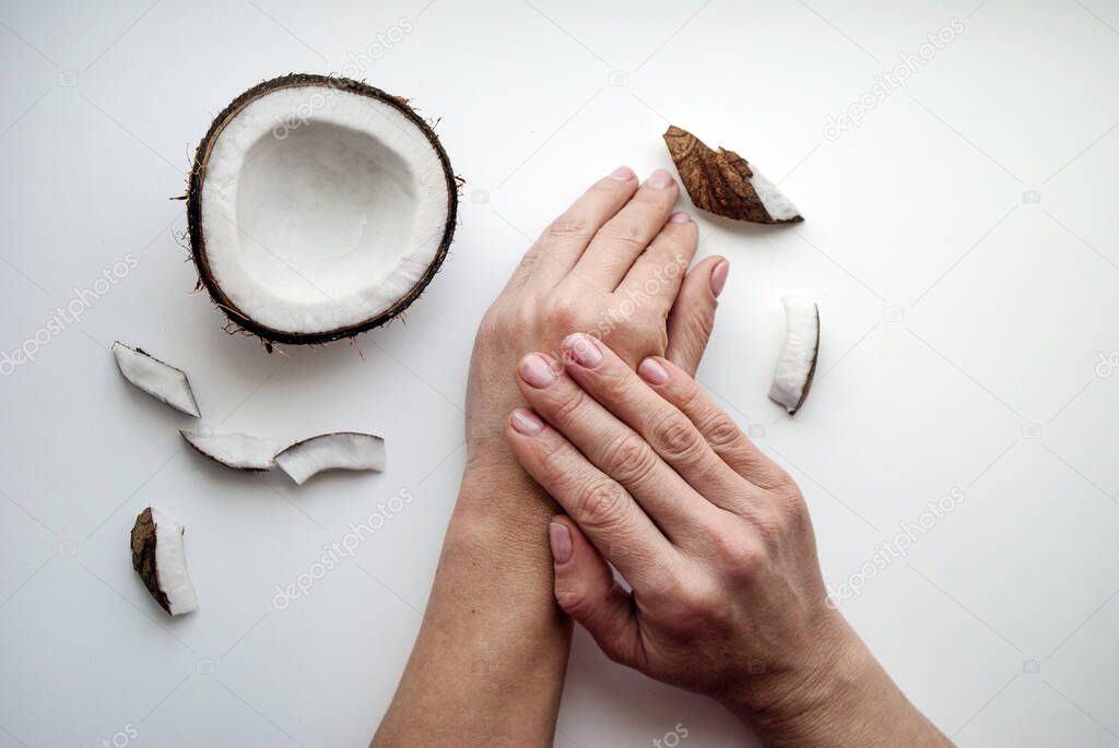Woman smears her hands with natural cream. Female hands close-up top view. Organic cosmetics with coconut on white background top view mockup. 
